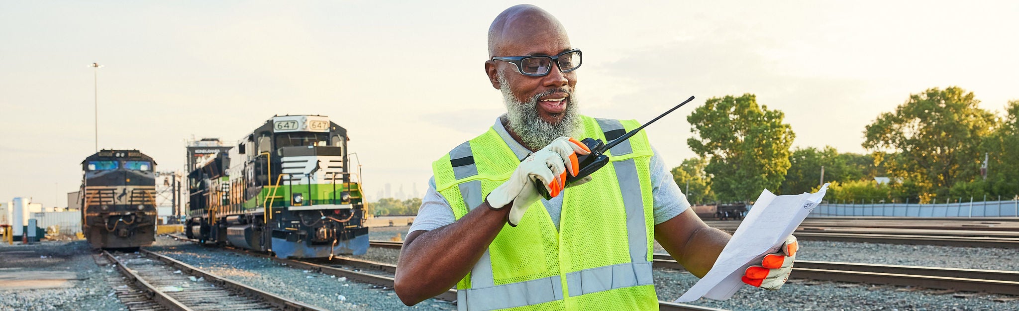 Close up of Norfolk Southern employee in safety vest standing on the front of an eco train thinking about customer centric strategy